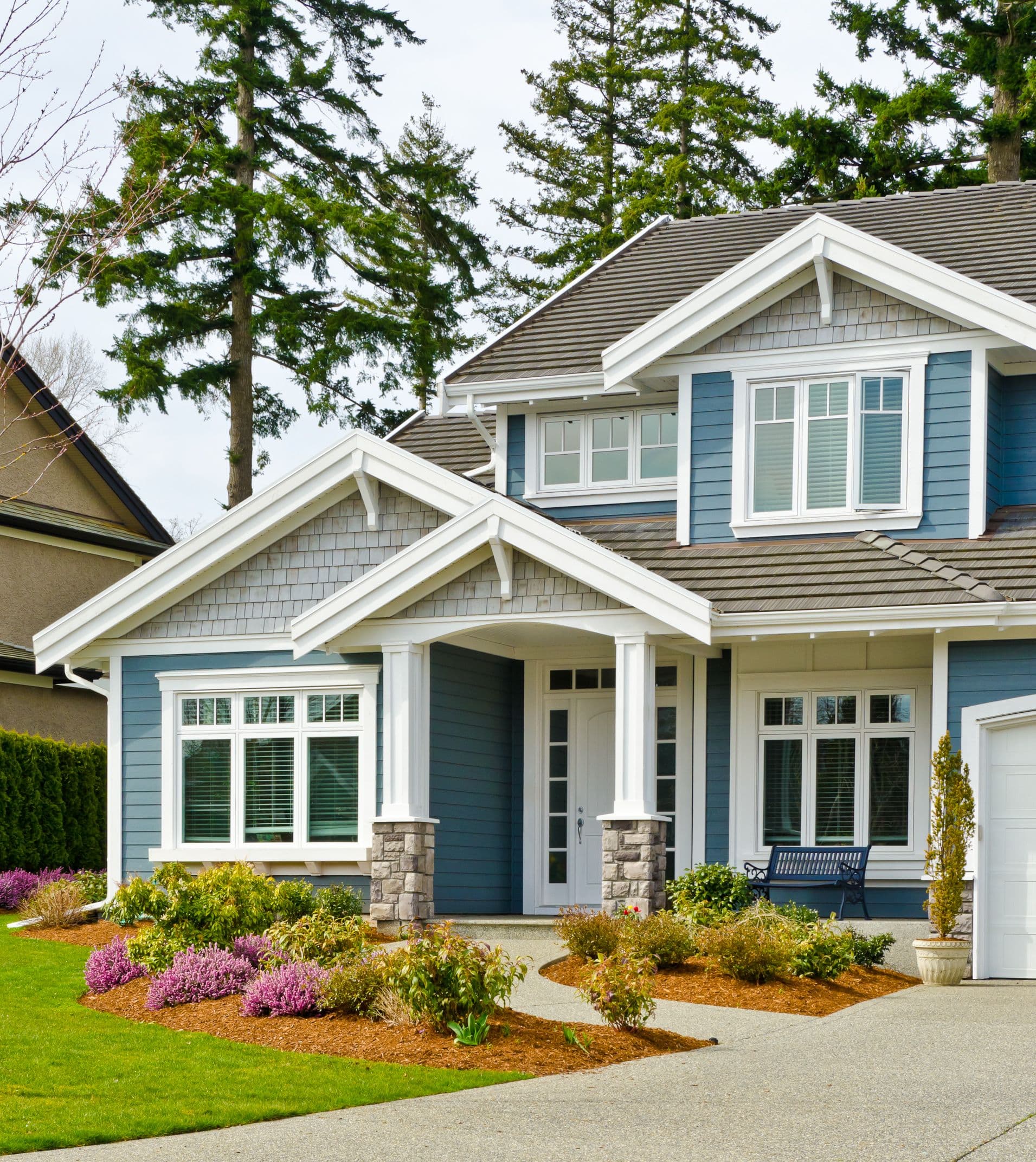 A blue house with white trim and a large garden out front.